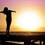 woman on beach at sunset arms outstretched