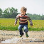 boy jumping above a puddle