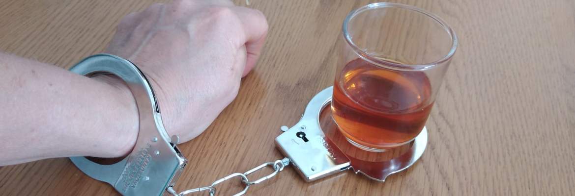 womans hand handcuffed to glass of whisky
