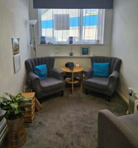 room with comfy chairs, plants, white walls in St Austell